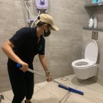 cleaner using toilet squeegee to dry out the toilet floor after washing